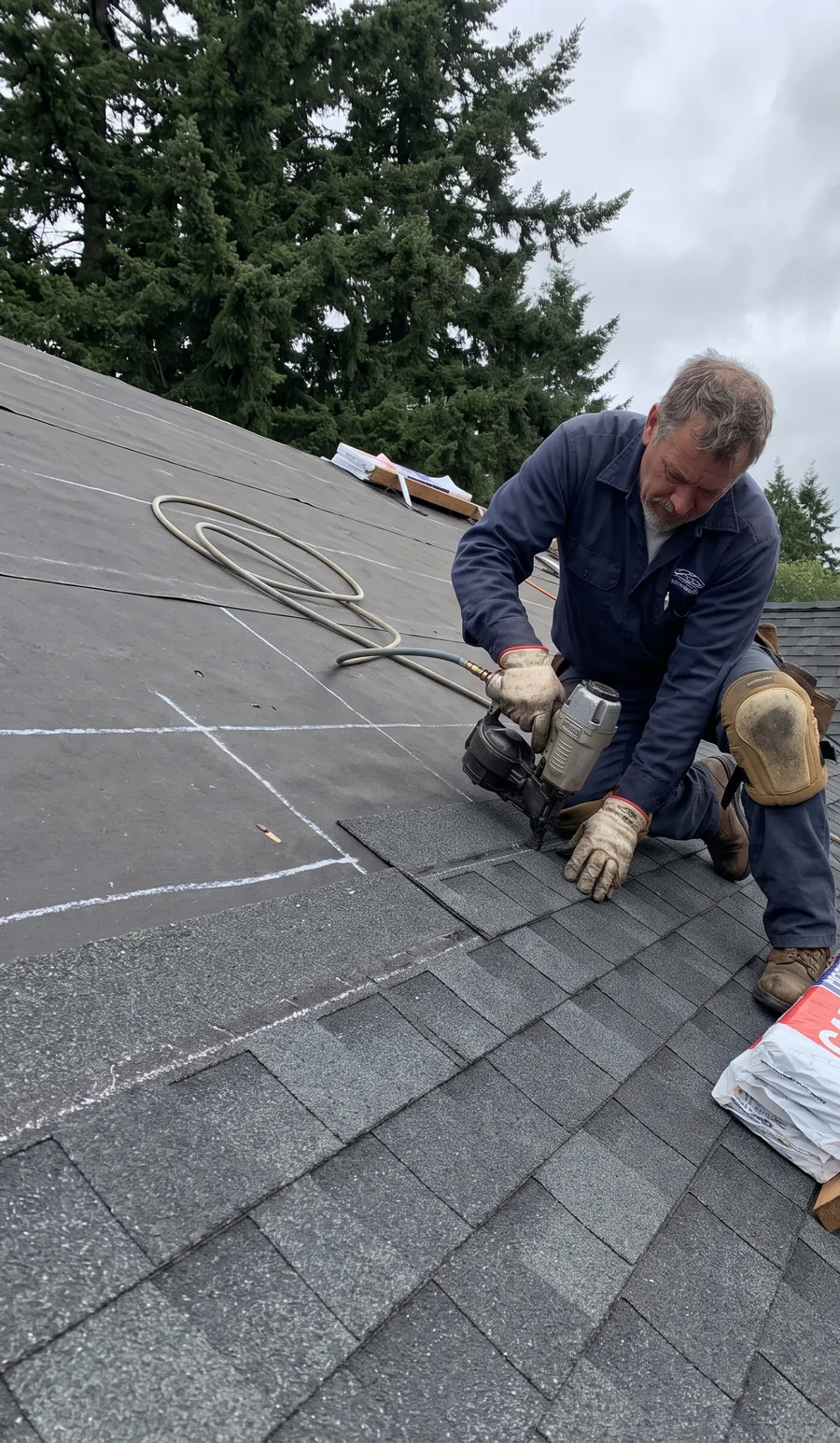Roofer nailing a course of architectural asphalt shingles